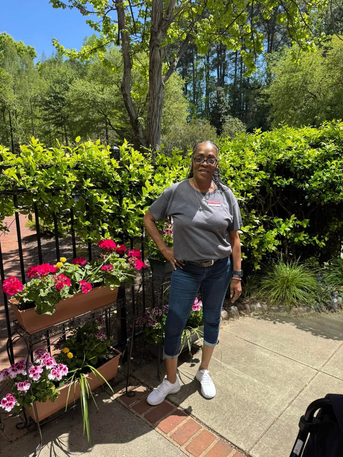 SarahCare of Lake Boone Trail team member standing outdoors beside colorful flowers.
